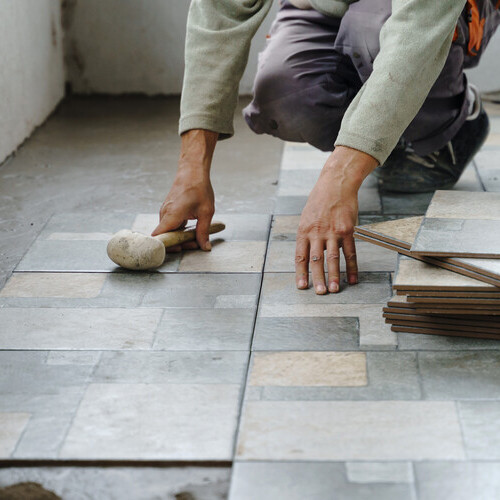 Contractor installs tile flooring.